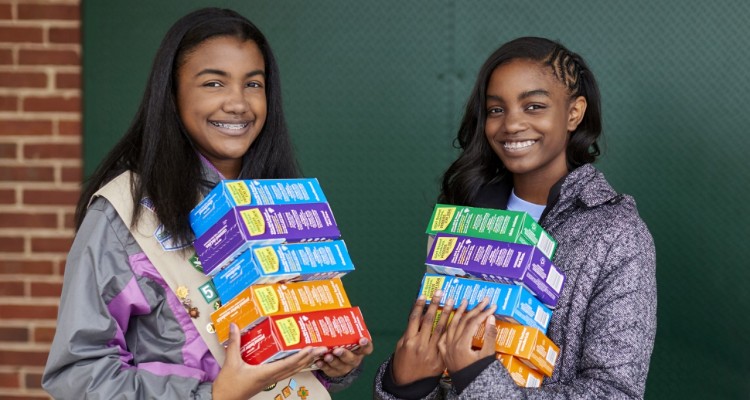 Smiling Girl Scout Holds Cookie Boxes